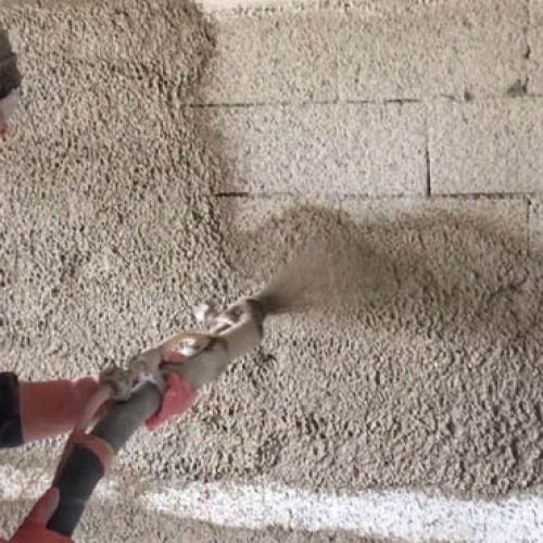 Spray application of Ideal Drymix plaster on block wall