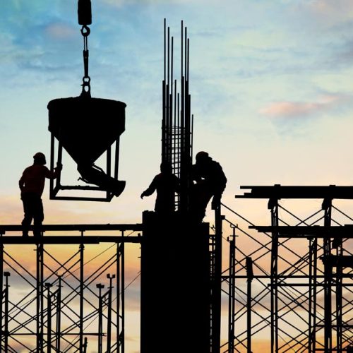 Construction workers placing concrete using crane on building structure at site