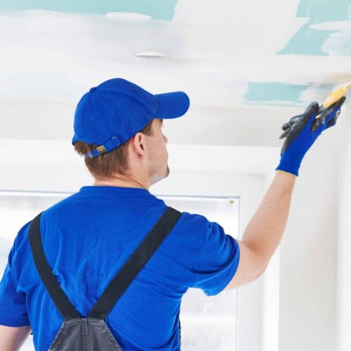 Worker applying wall putty on ceiling and wall edges for smooth interior finish
